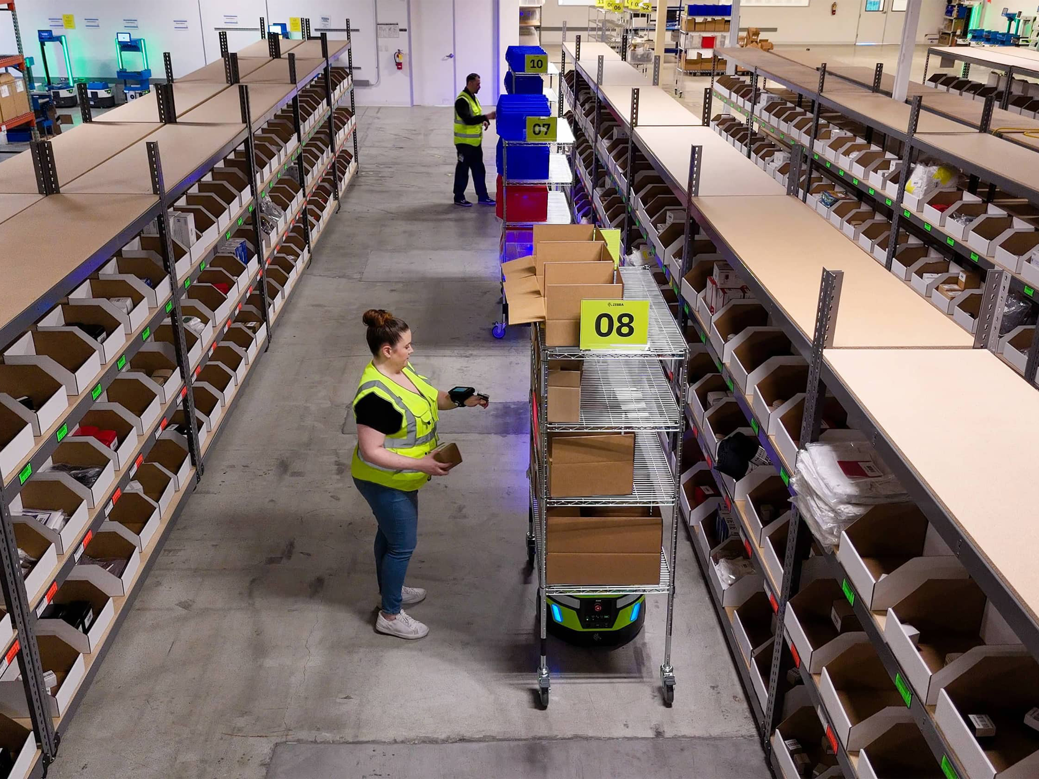 zebra-symmetry-fulfillment-photography-application-in-aisle-multiple-robots-pickers-overhead.jpg