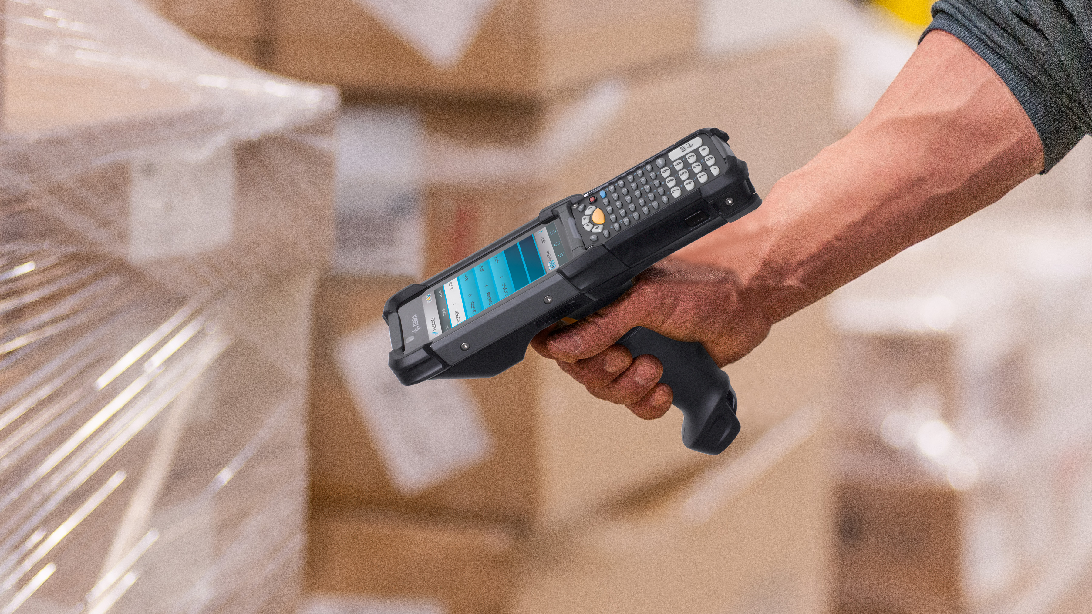 Worker uses a handheld Zebra mobile computer to scan barcodes on cardboard boxes