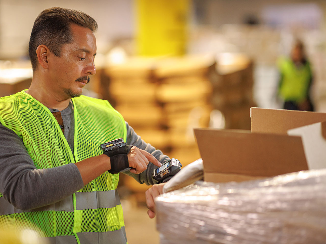 Worker using wearable Zebra mobile computer and head mounted display to scan boxes on a wood pallet