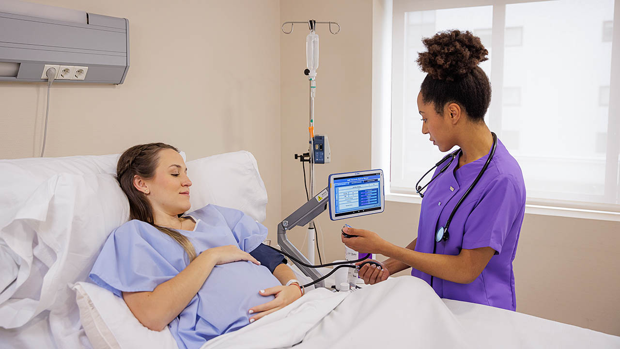 Nurse assisting a female patient bedside