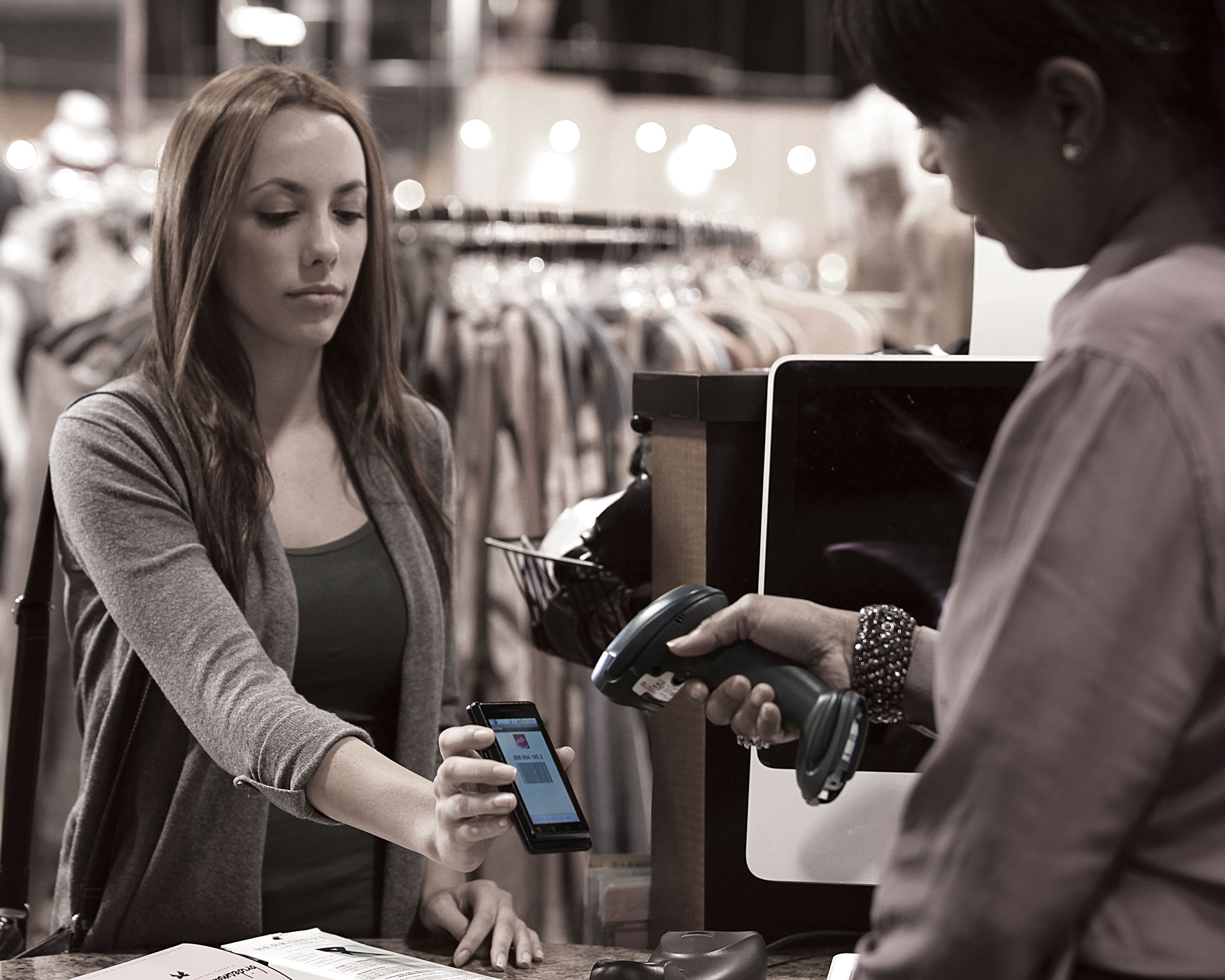 Retail clerk uses Zebra LI4278 handheld scanner to scan a barcode on a mobile phone screen