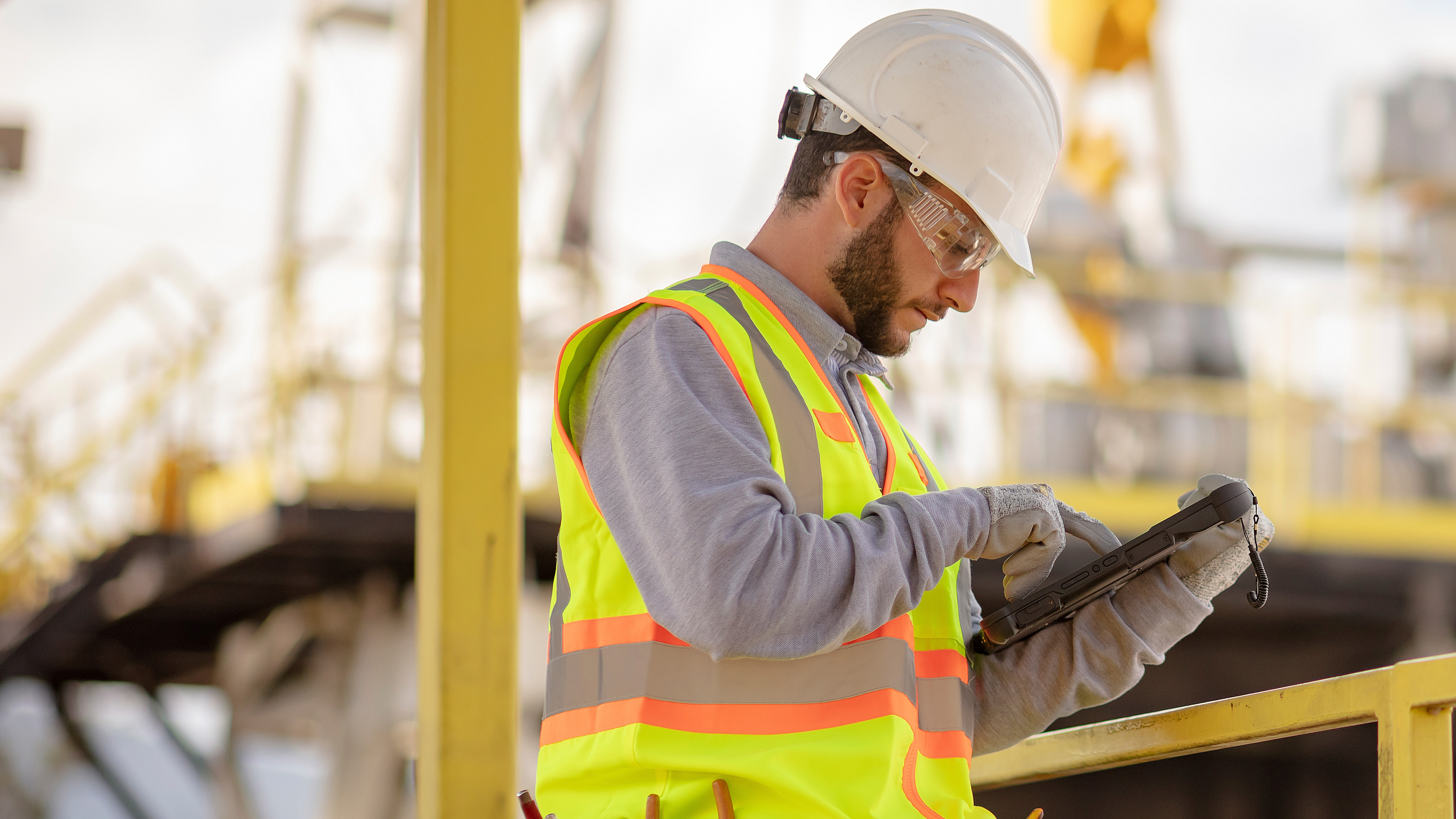 Utilities worker with white hard hat using a zebra tablet
