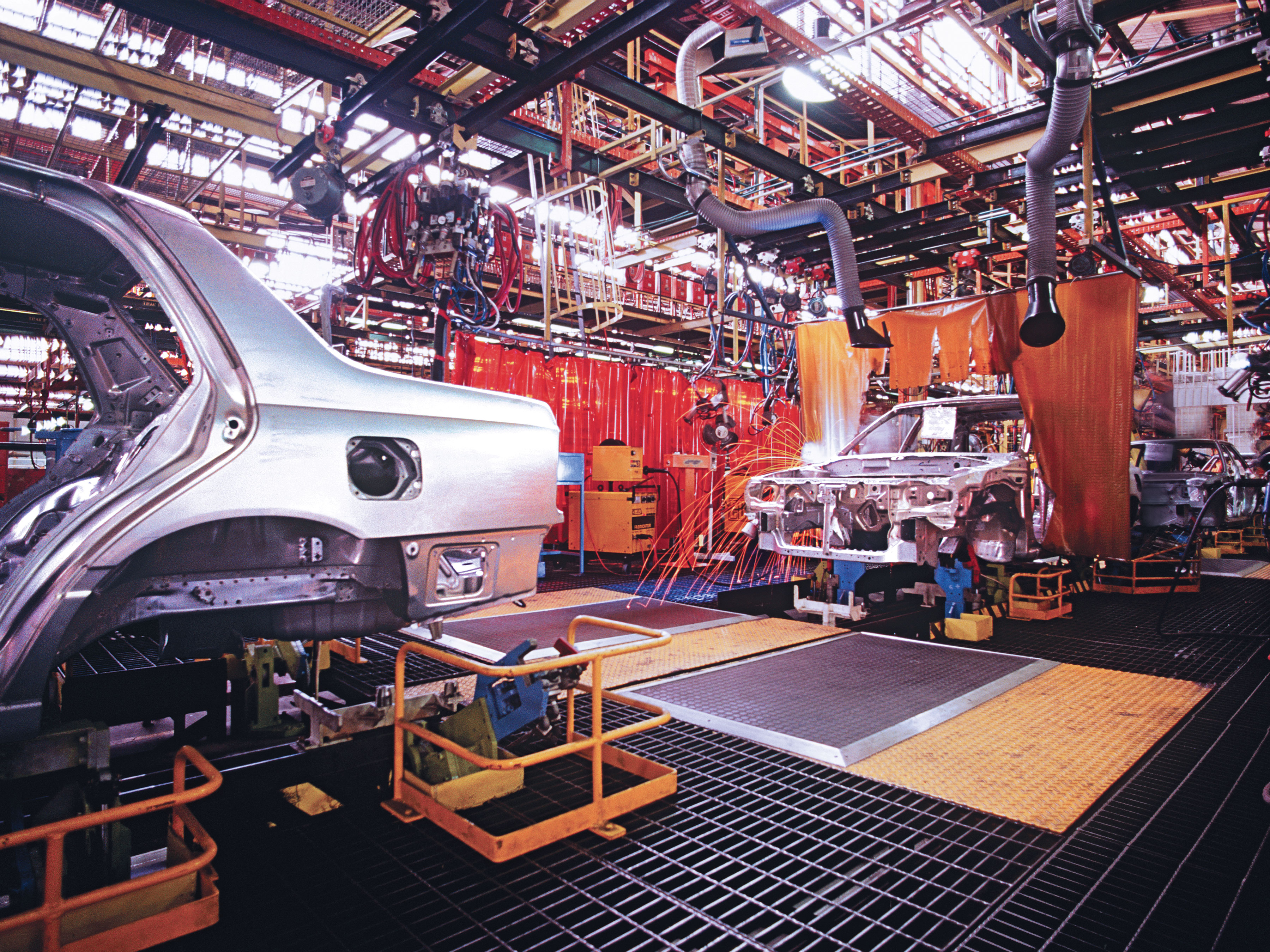 Photograph inside a car manufacturing plant of cars on the line