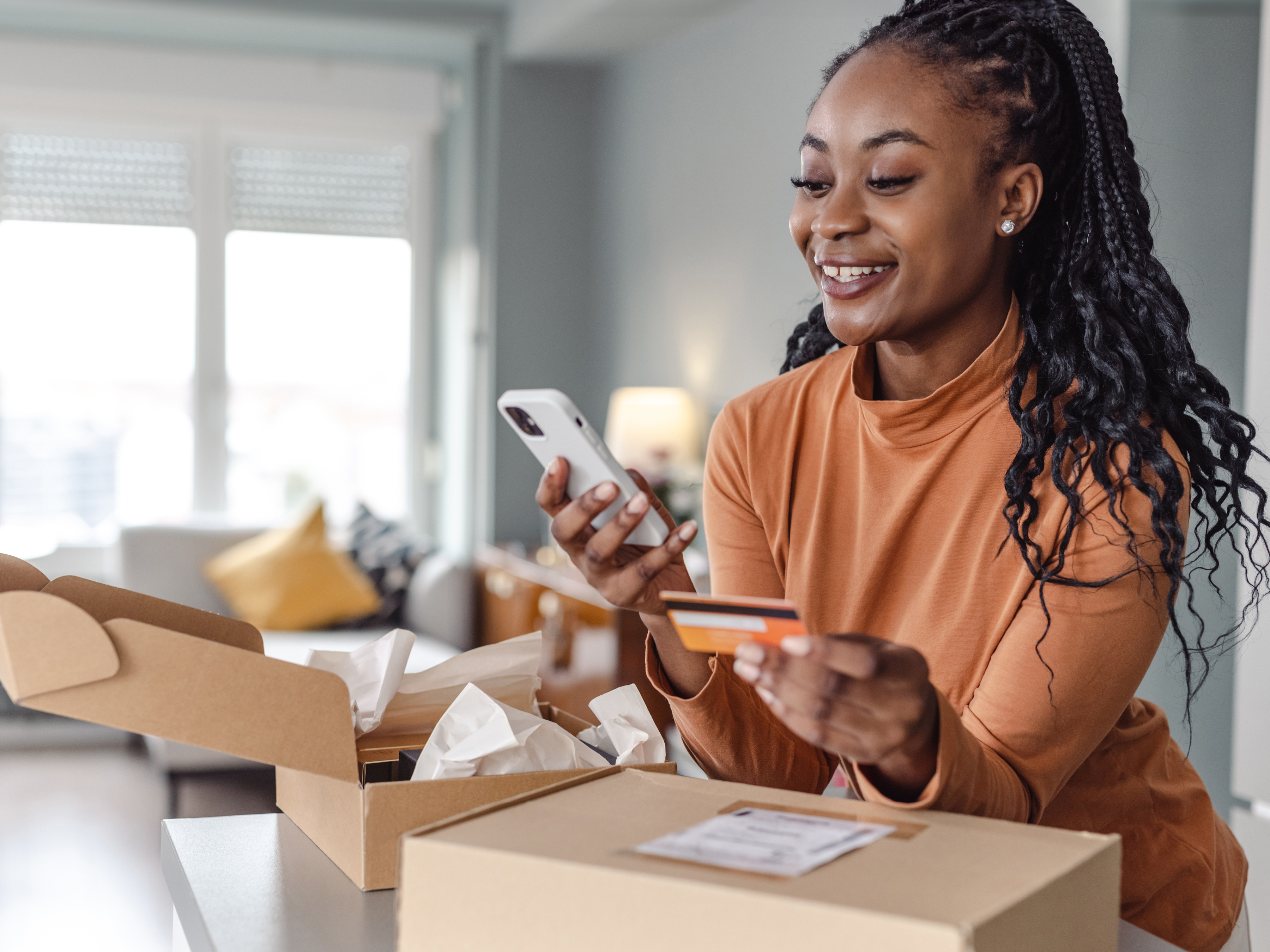 Woman looking at her phone holding a credit card