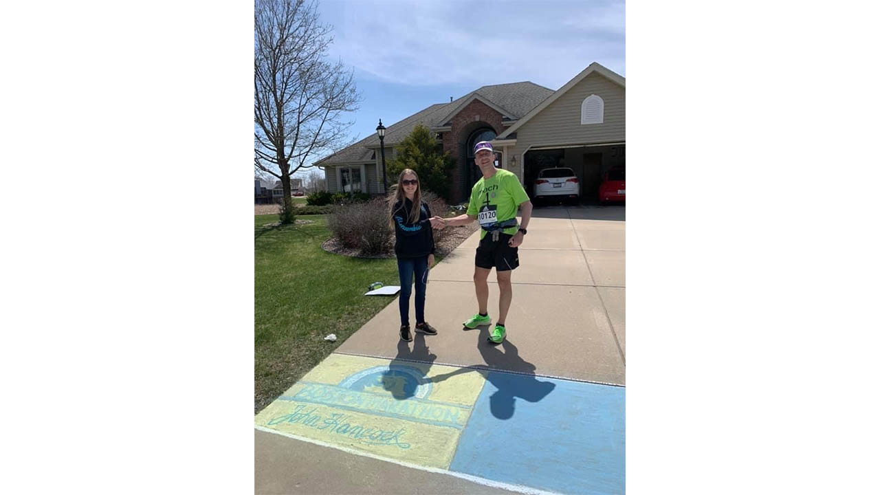 Joe Zons' daughter presents him with his trophy after running a DIY marathon in his hometown