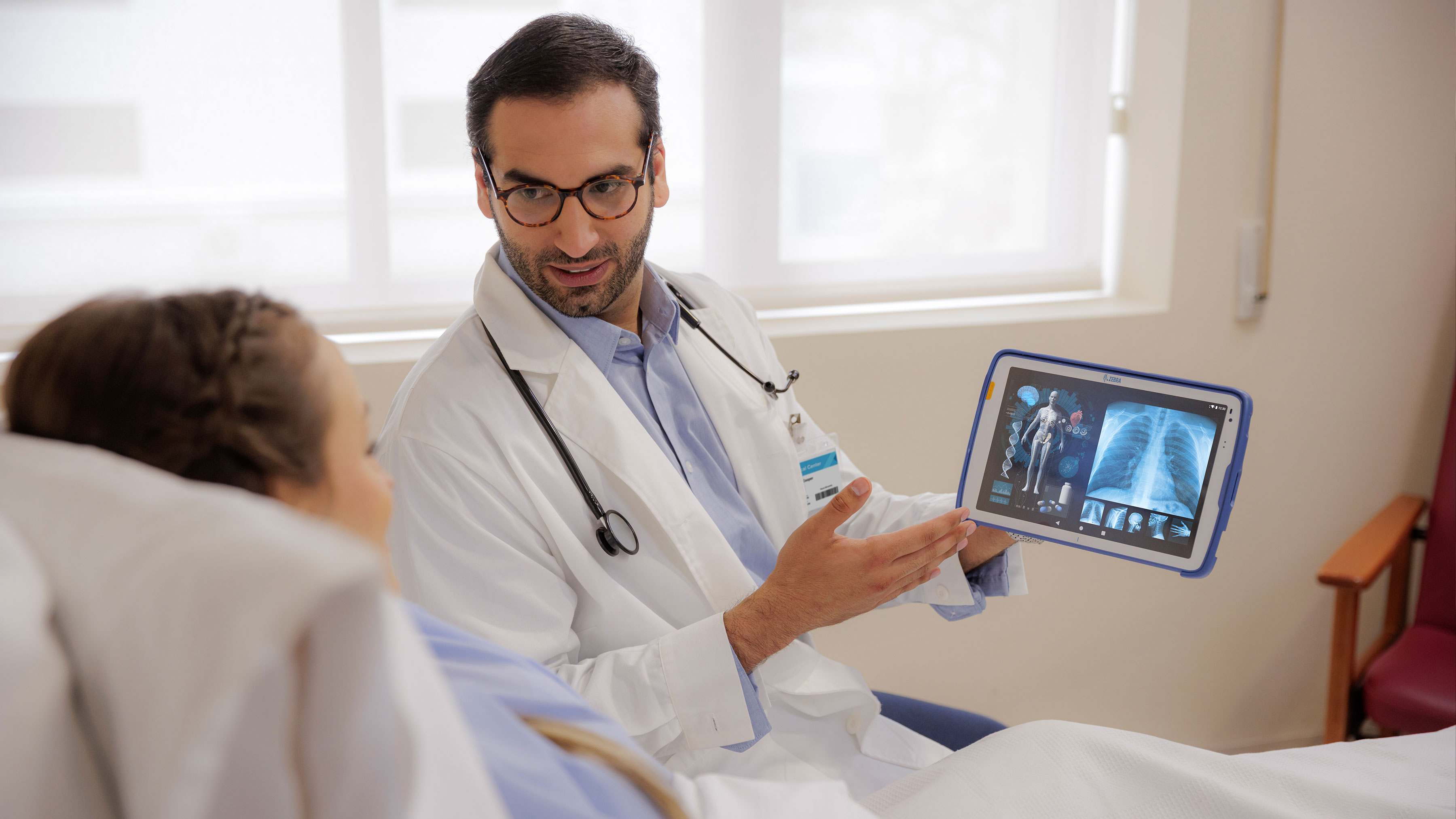 Doctor showing a patient information using a Zebra healthcare tablet.
