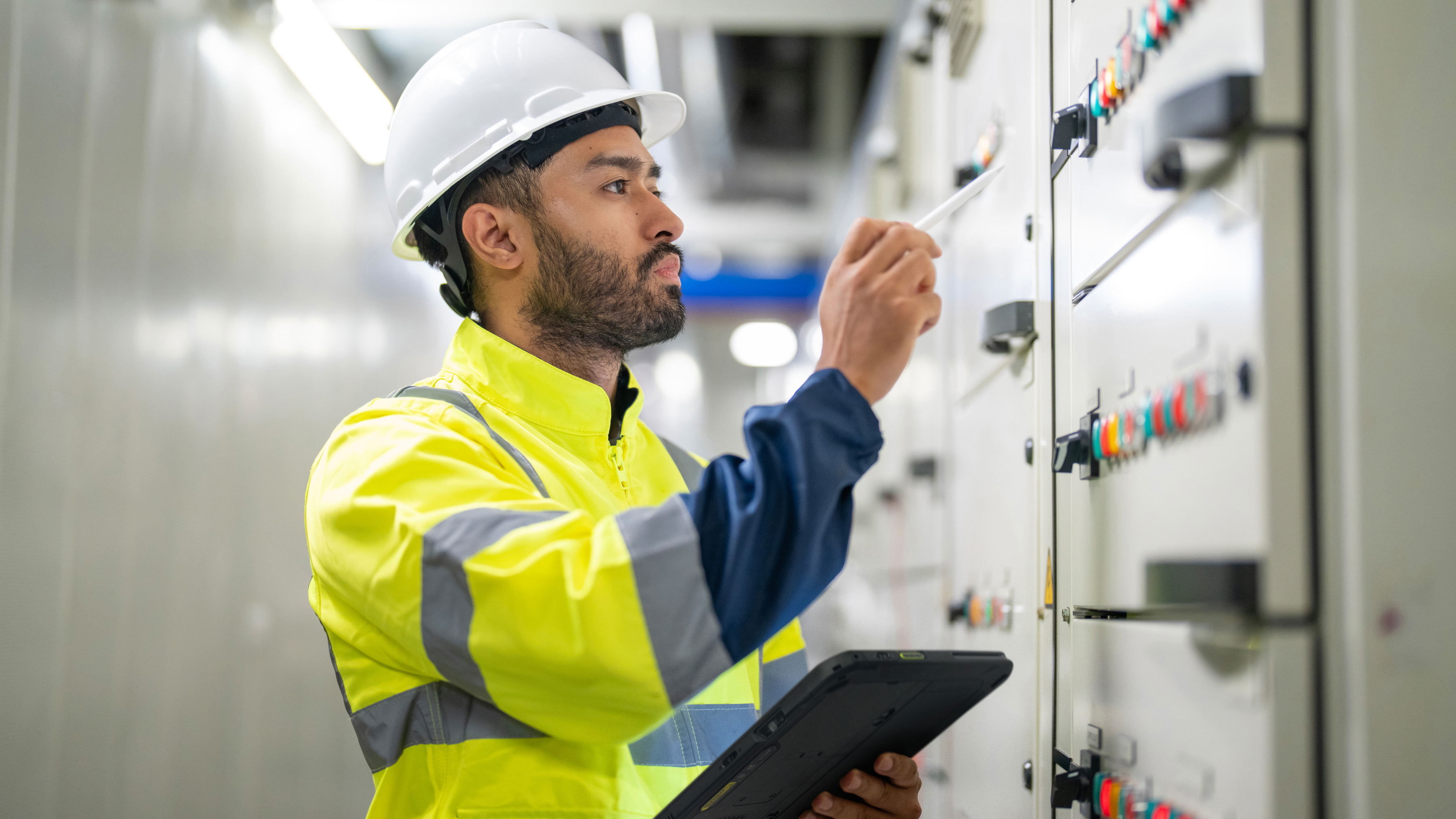 An engineer inspecting a control panel inside of an industrial facility.