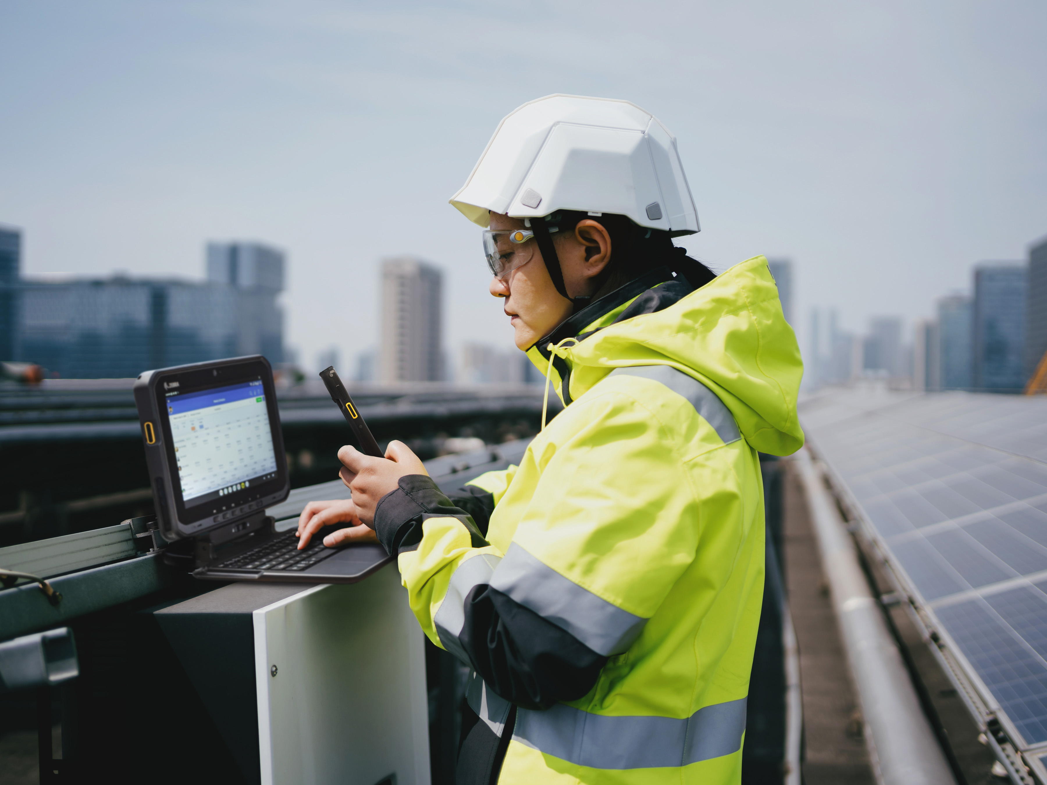 Worker using a Zebra handheld mobile computer and a Zebra tablet while at  solar power station.