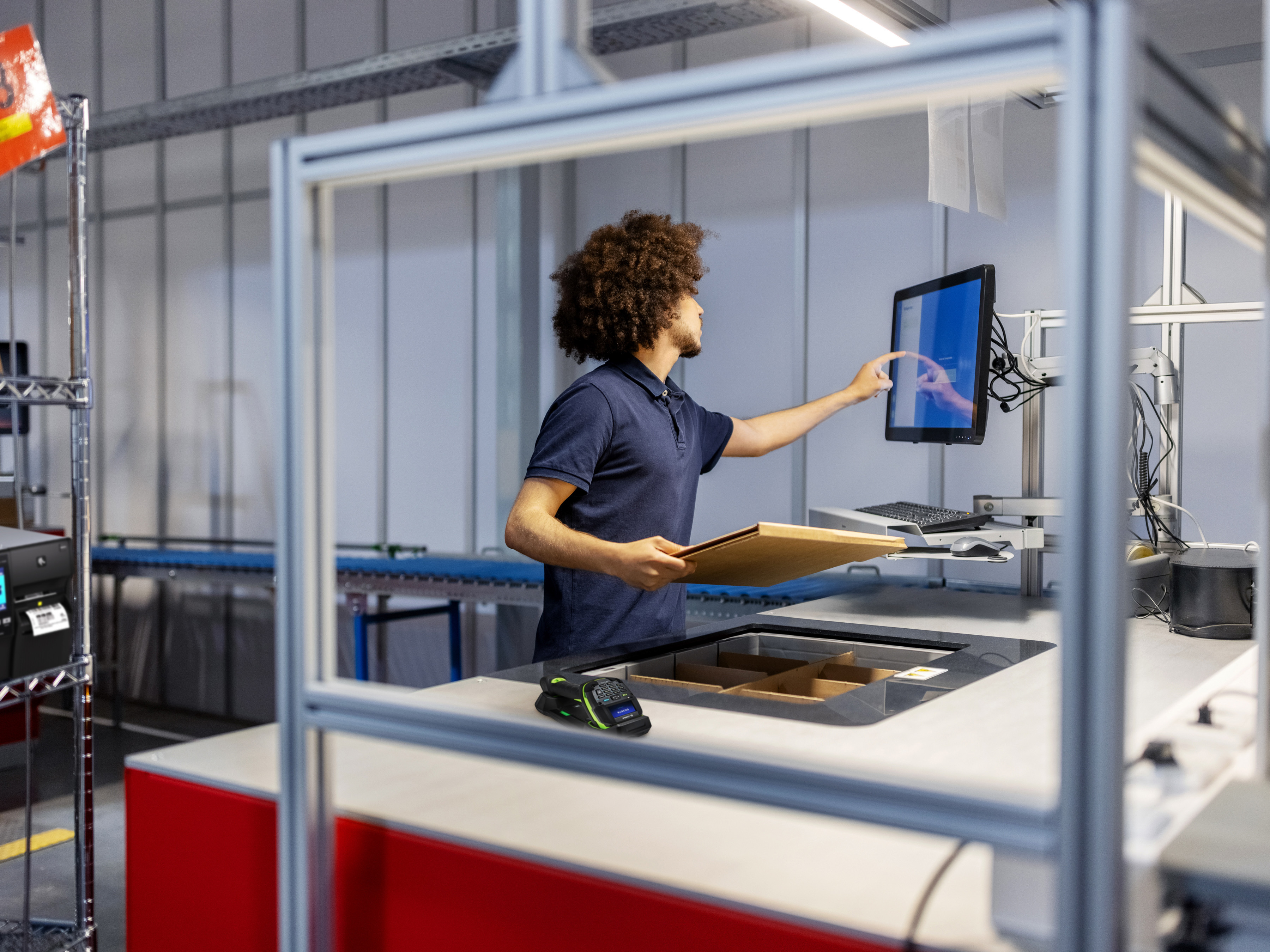 A warehouse worker processes a package on a workstation with a Zebra Industrial printer.