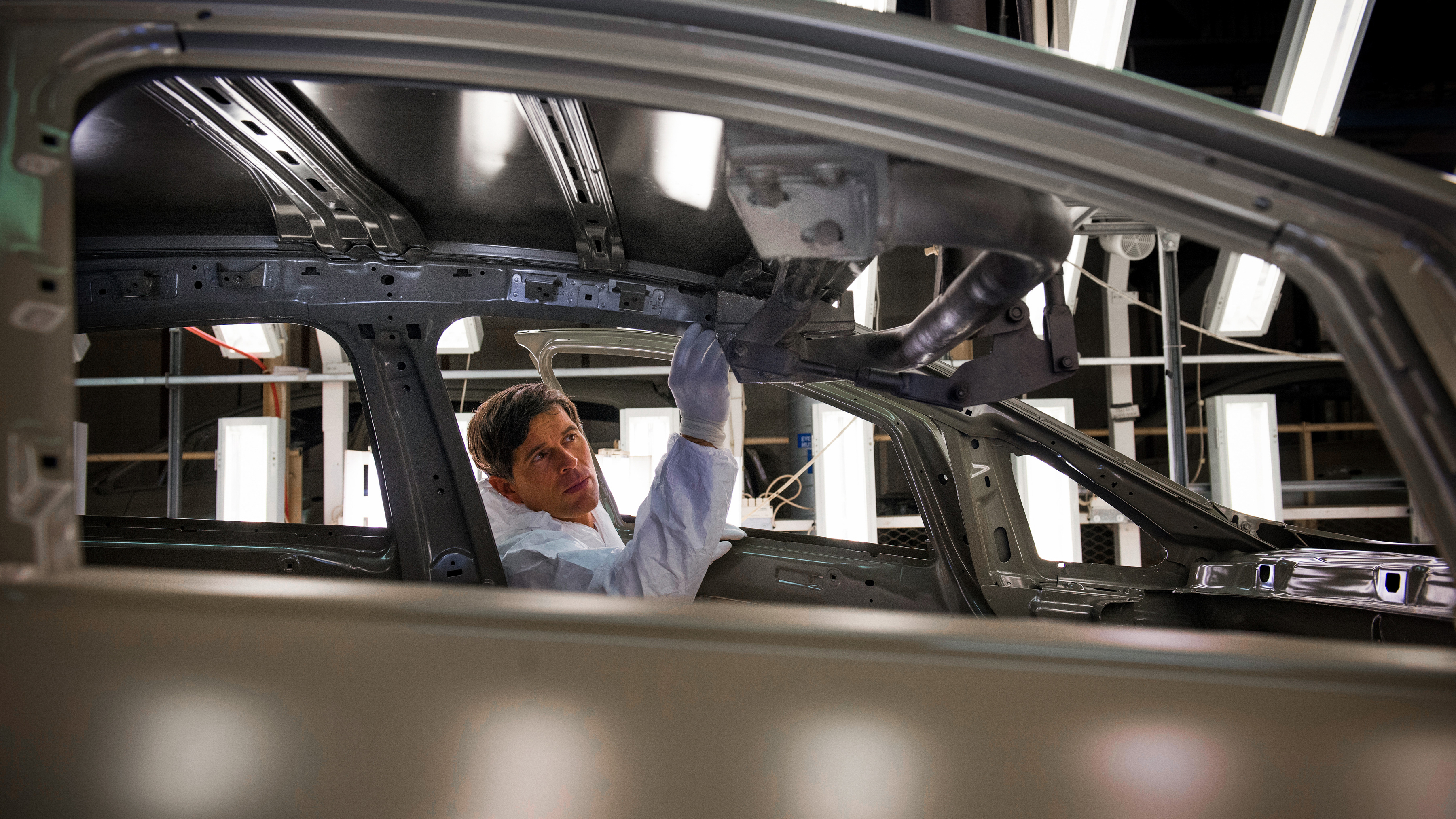 Manufacturing worker inspecting a car on the production line.