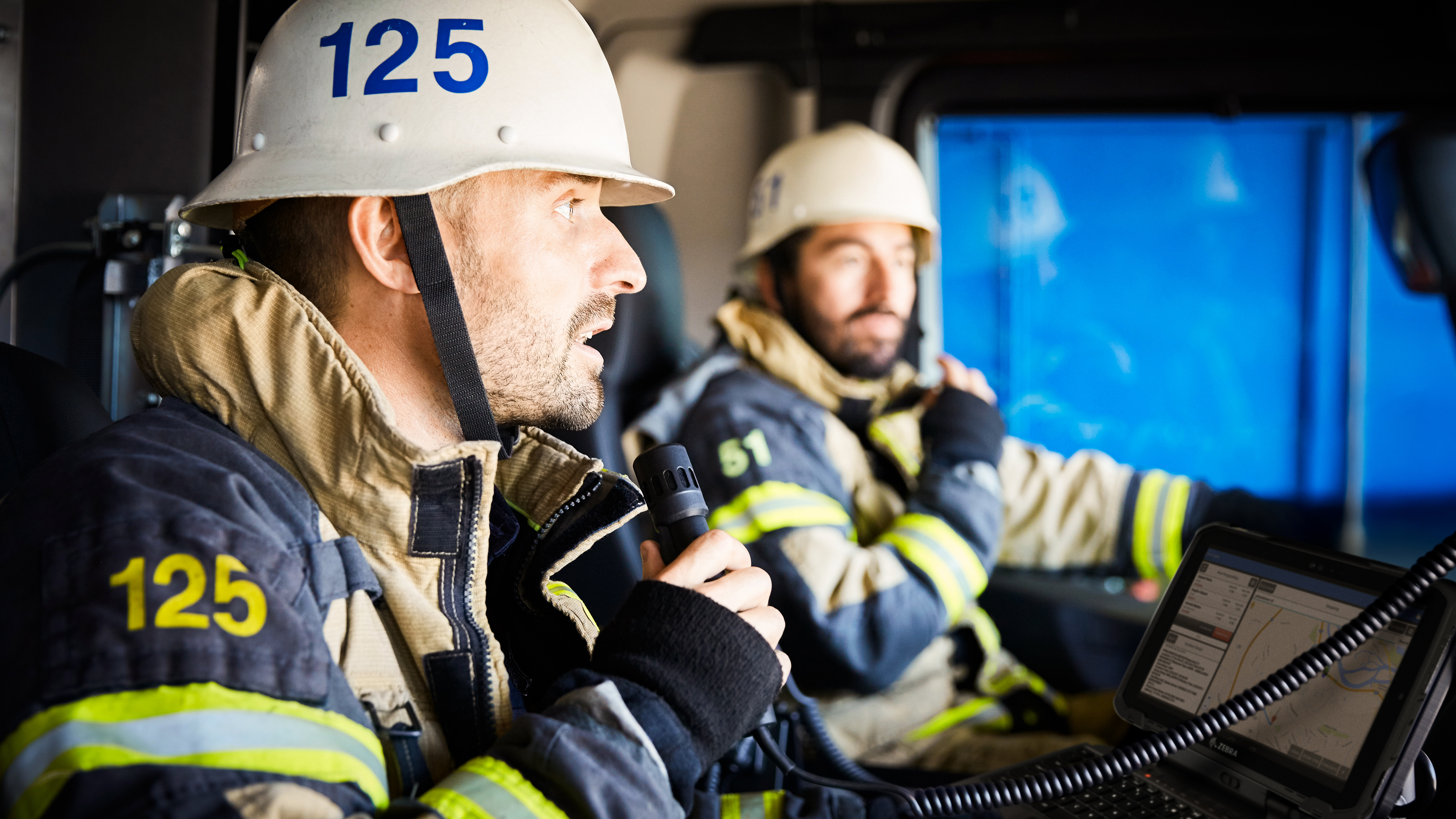 Two firefighters reviewing a Zebra ugged tablet inside of a firetruck.
