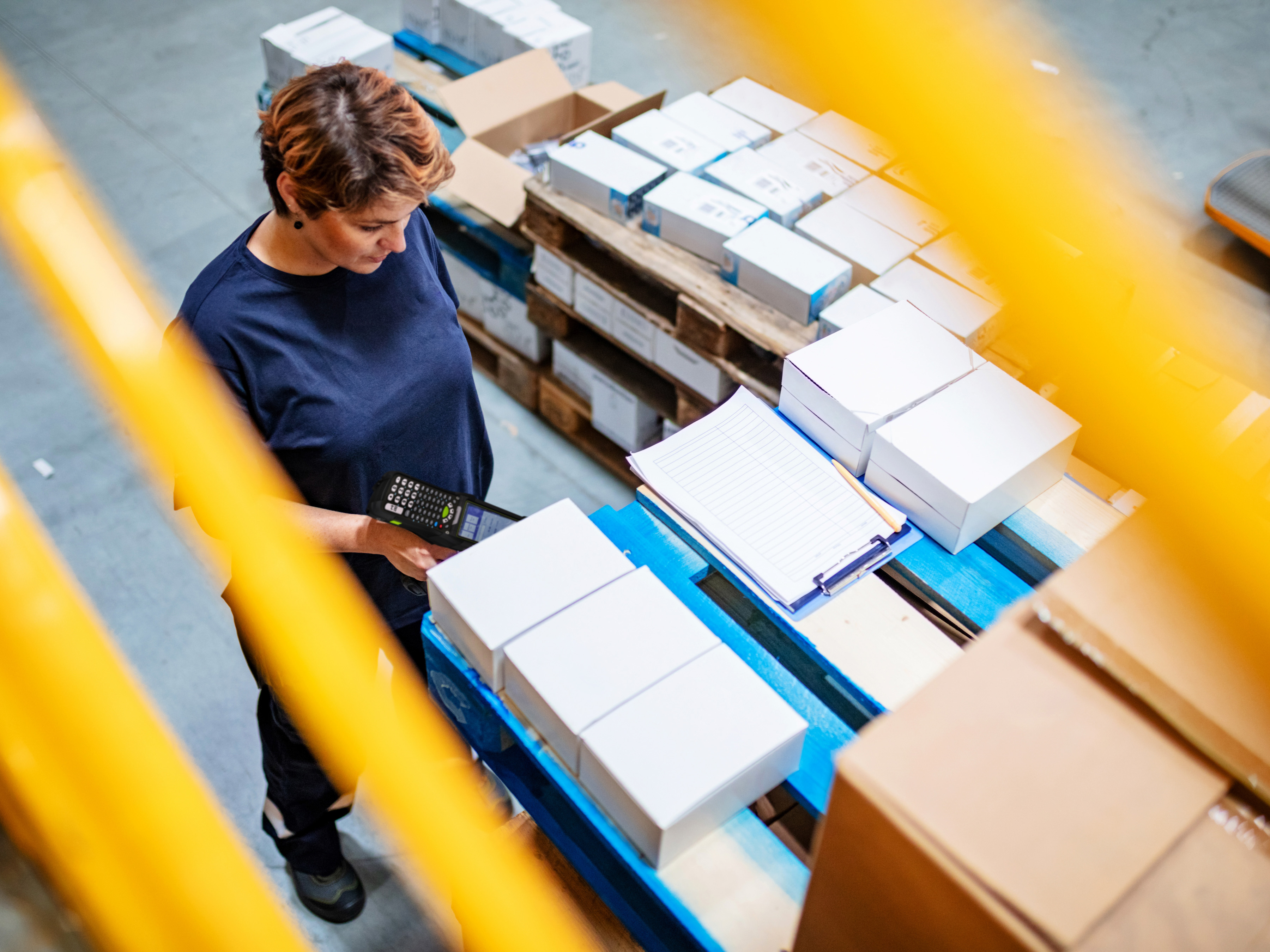 Retail worker using a Zebra handheld mobile computer to scan boxes on a pallet.