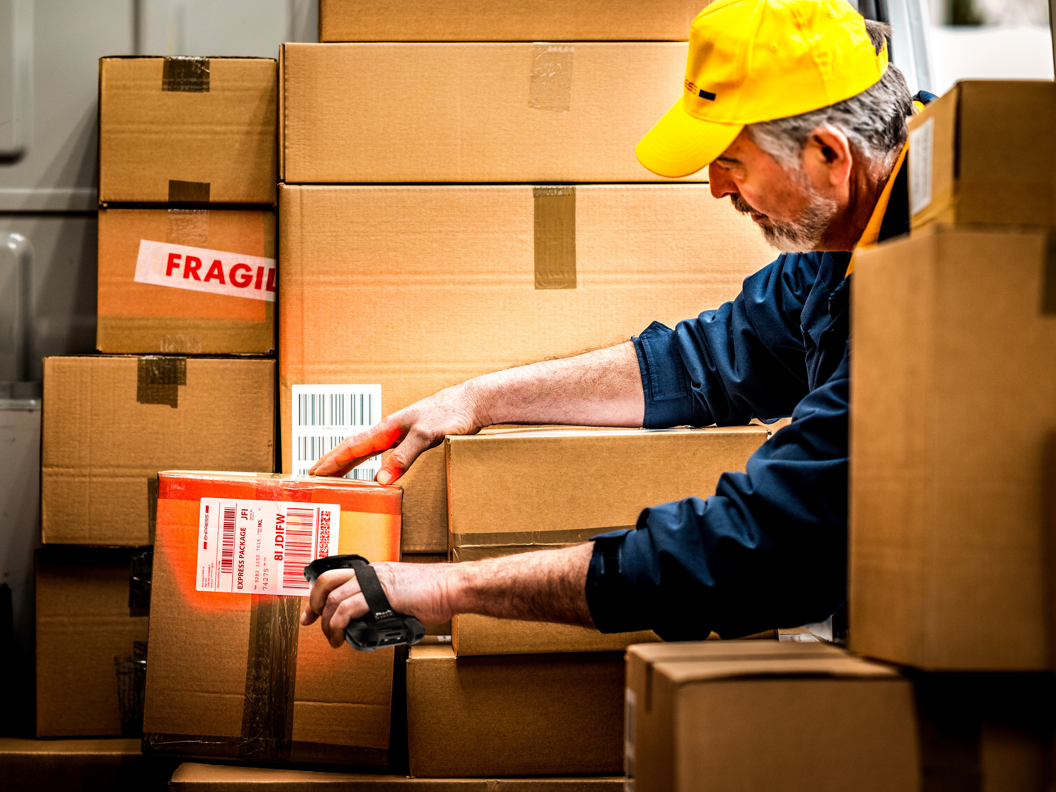 A driver using a handheld mobile computer to scan packages inside of a delivery truck.