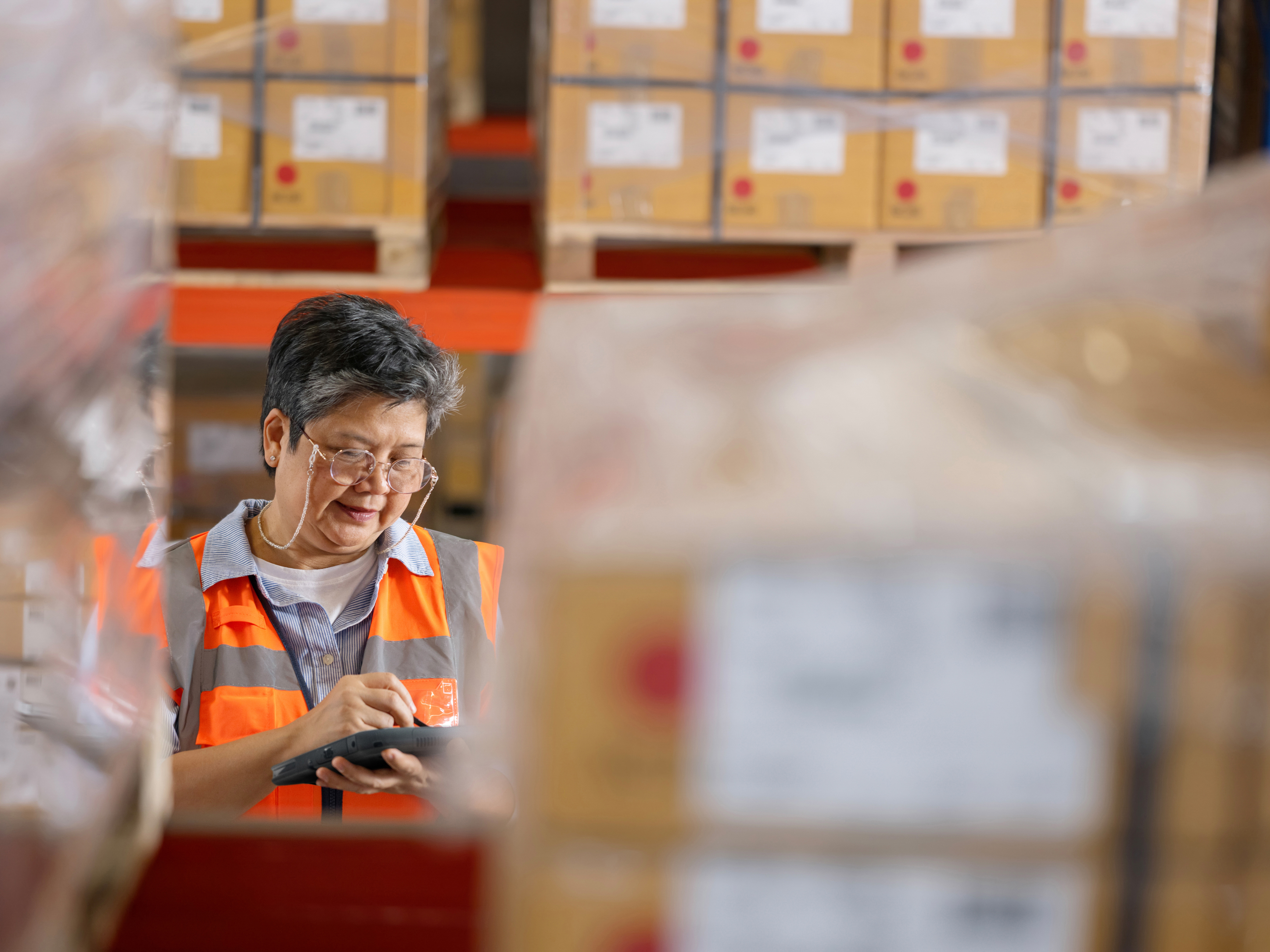 An employee checking a pallet with a tablet inside of a warehouse.